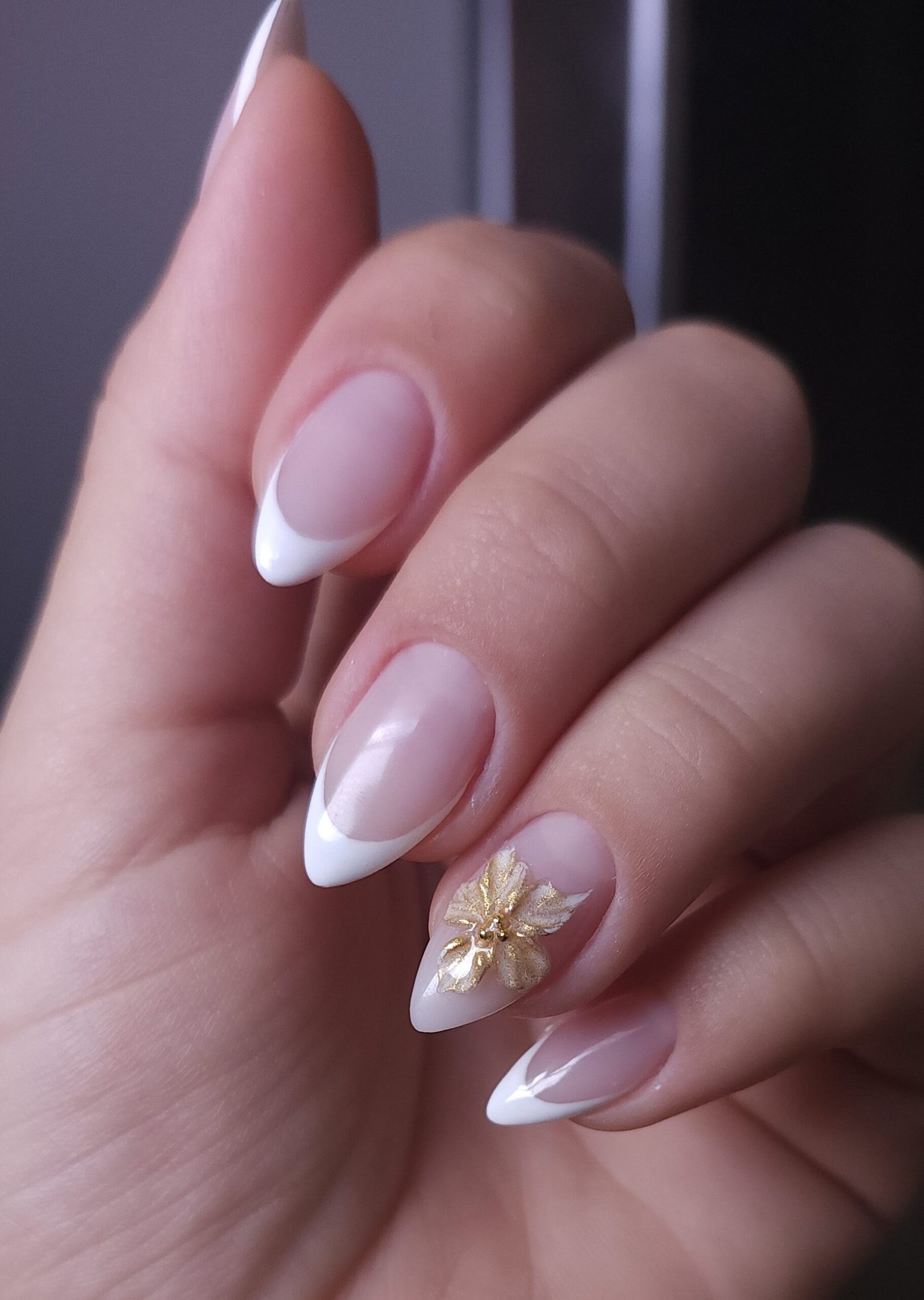 Classic French tip manicure with a gold floral accent nail