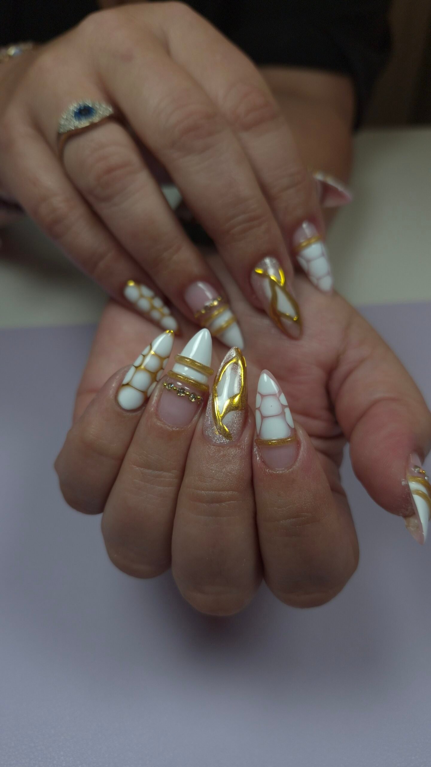 Long stiletto builder gel extensions in milky white and nude with gold chrome accents, 3D white dot designs, and a rhinestone line by Nails by Odett in Naples, FL